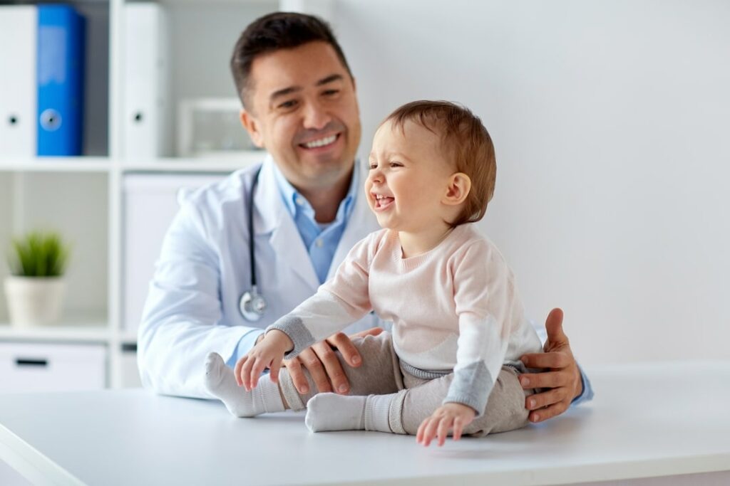 A doctor with a child sitting on an examine table.